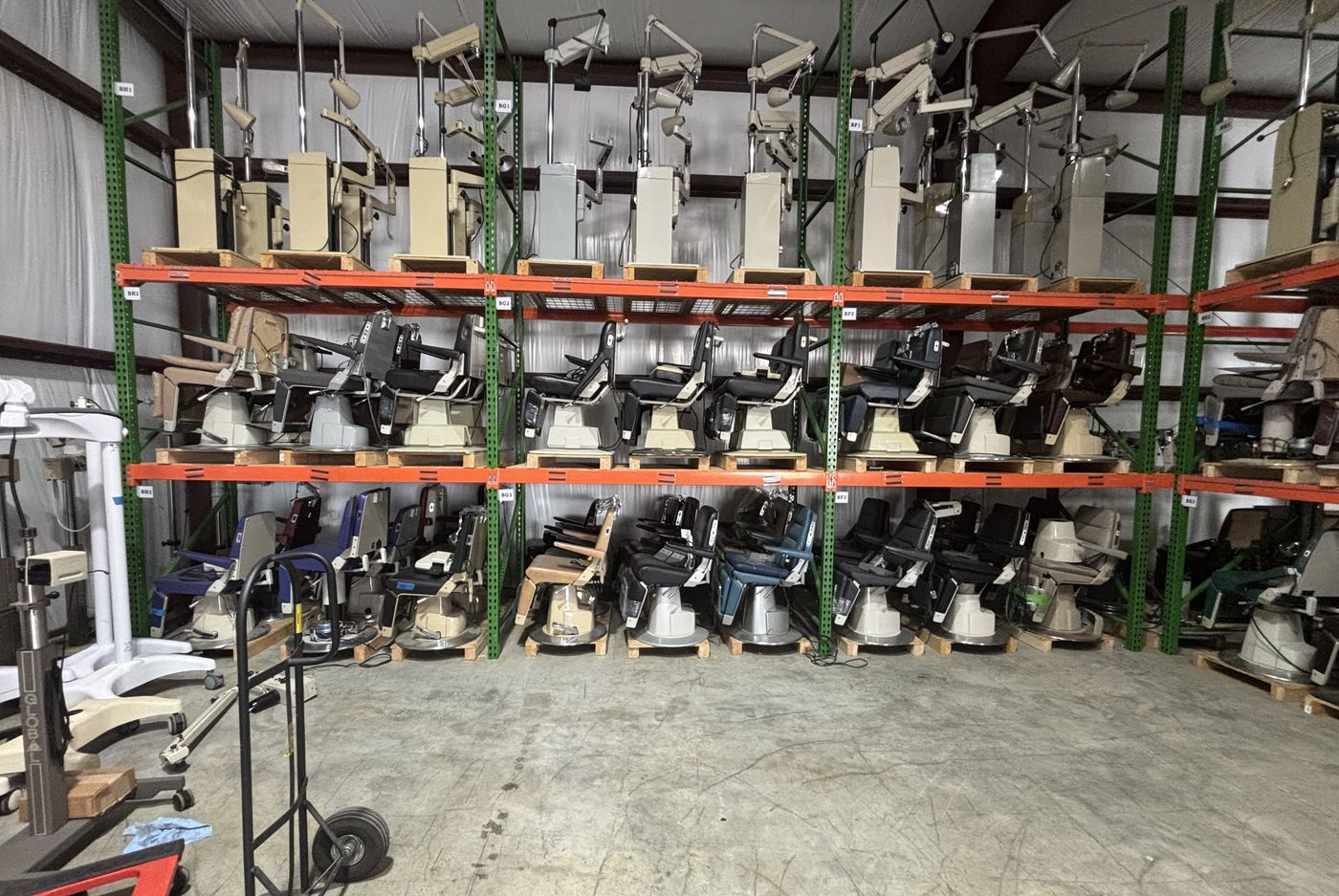 Racks of exam chairs and instrument stands in a warehouse